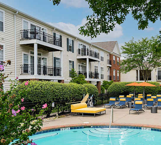 a swimming pool with lounge chairs and umbrellas in front of a building