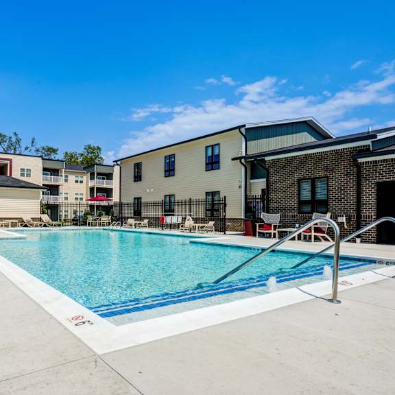 A swimming pool in front of a building with a blue sky in the background.