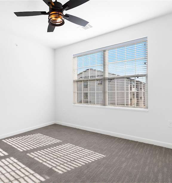 A room with a ceiling fan and a window with blinds.