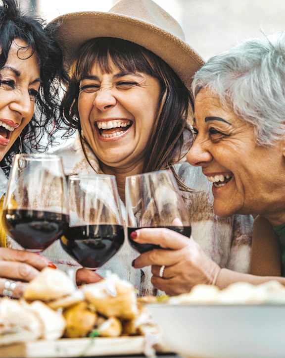 three women sitting at a table with glasses of wine
