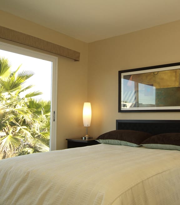 model bedroom with view of palm trees from balcony