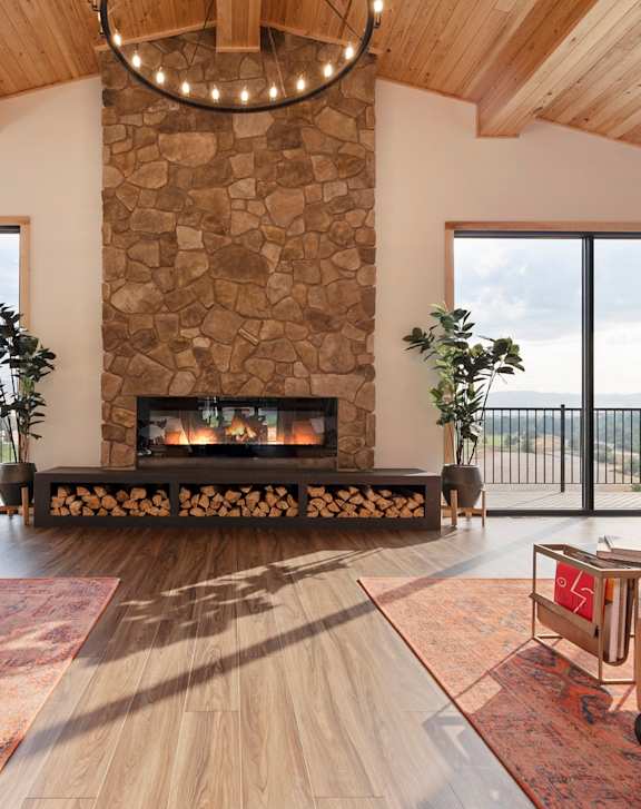 A modern living room with a stone fireplace and a large window.
