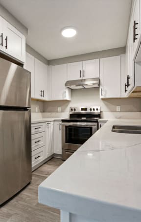 a large kitchen with white cabinets and stainless steel appliances at Citra Apartments LLC, California, 92107