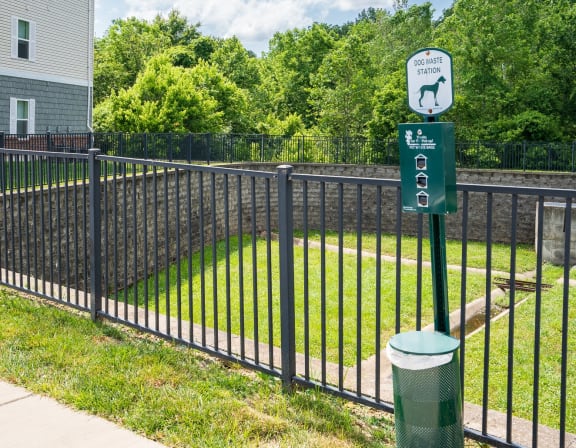 a black wrought iron fence with a green sign on it and a yard behind it
