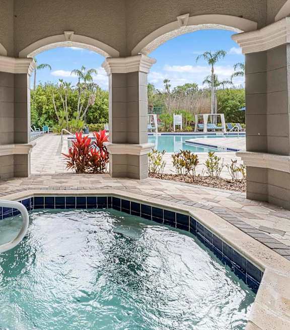 A pool surrounded by a stone patio and arches.