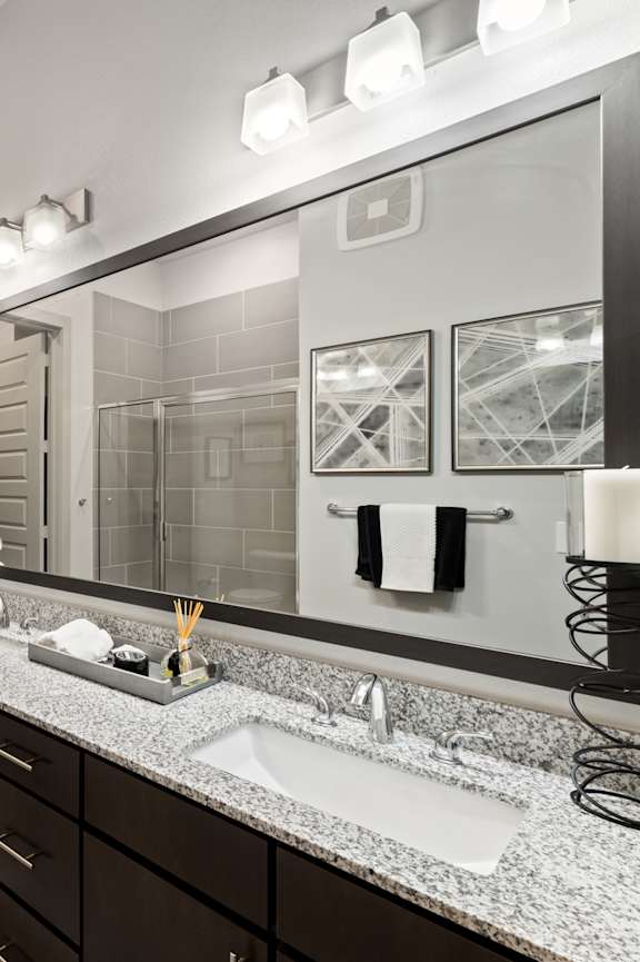 A bathroom with a sink, mirror, and a shower.