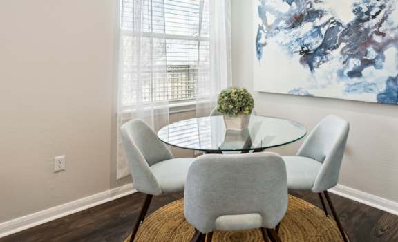 A dining room with a round table and grey chairs.