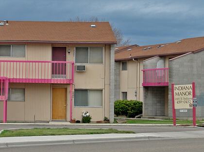 Apartment complex with cars parked in front.
