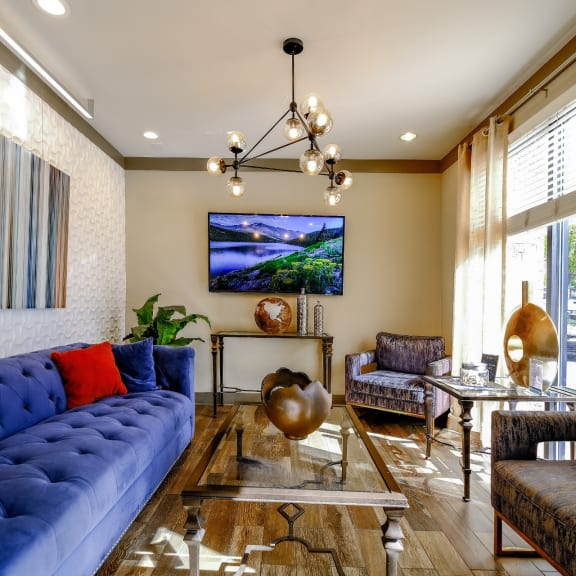 a living room with blue couches and chairs and a glass table