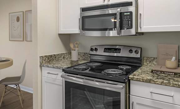 A kitchen with a stove, microwave, and refrigerator.