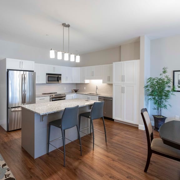 A modern kitchen with a stainless steel refrigerator and wooden flooring.