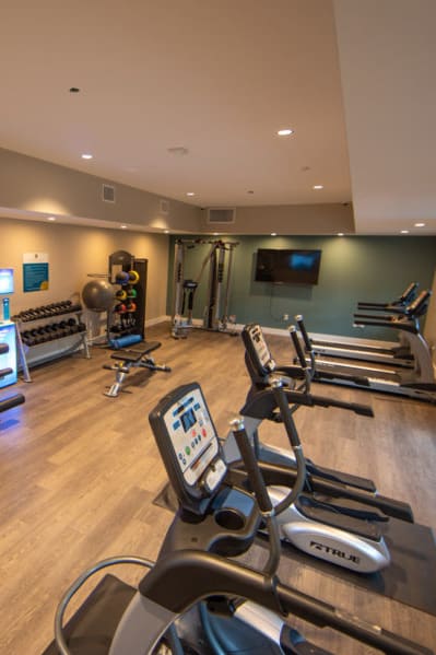 a gym with cardio equipment and a television at Aspire Upland Apartments, California, 91786