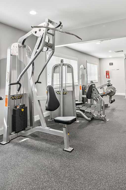 a workout room with treadmills and a tv