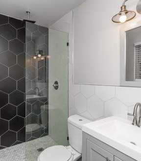 a bathroom with black and white tiled walls and a glass shower