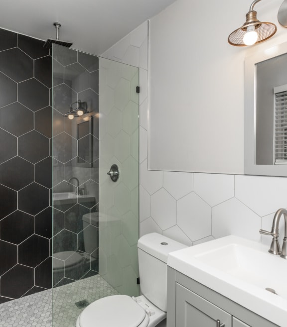 a bathroom with black and white tiled walls and a glass shower