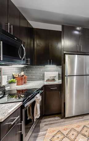 A modern kitchen with dark wood cabinets and stainless steel appliances.