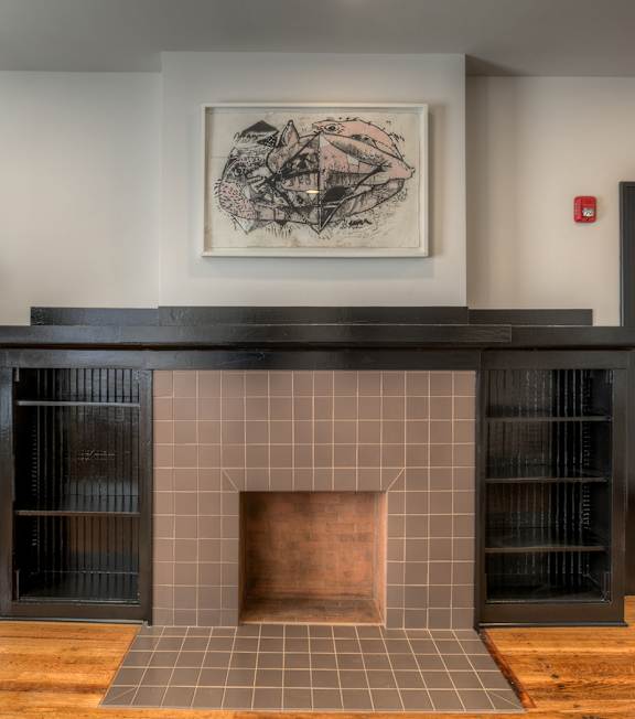 A fireplace with a black mantle and a framed picture above it.