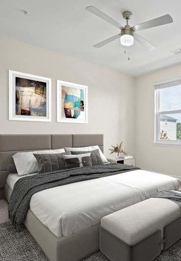 A bedroom with a large bed and two pictures on the wall.