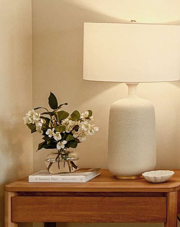 A bedroom with a bed, nightstand, and lamp.