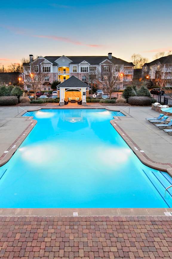 A large swimming pool surrounded by lounge chairs and umbrellas.