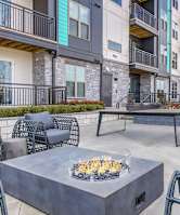 A patio with a fire pit and chairs.