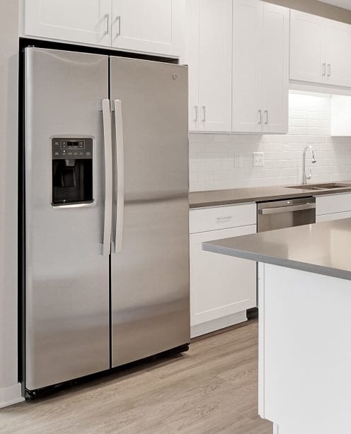 a kitchen with white cabinets and a stainless steel refrigerator