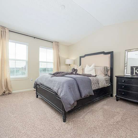 A bedroom with a large bed and a dresser with a mirror.
