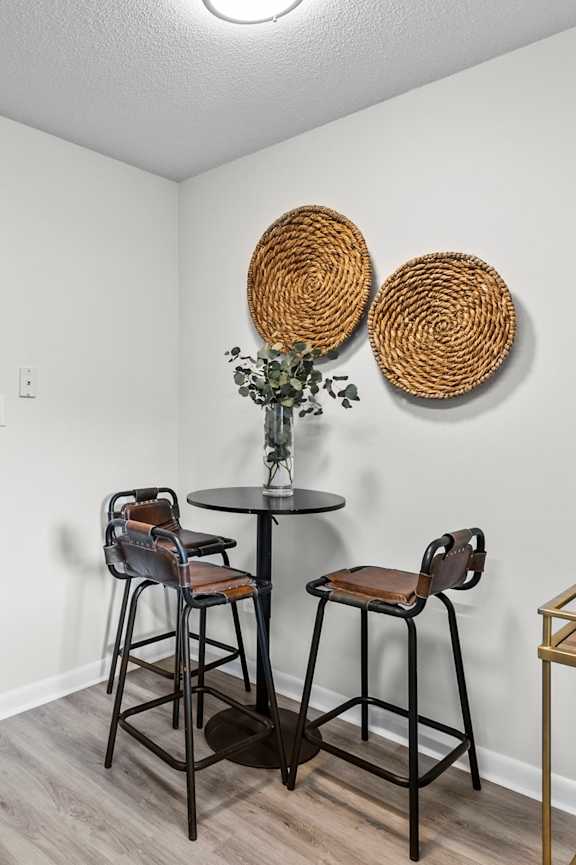 A living room with a bar stool and a table at West Oak Apartments, Wake Forest, North Carolina