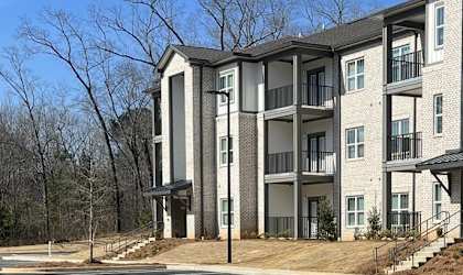 Apartment building with a parking lot in front at Arbours at Covington Apartments, Covington