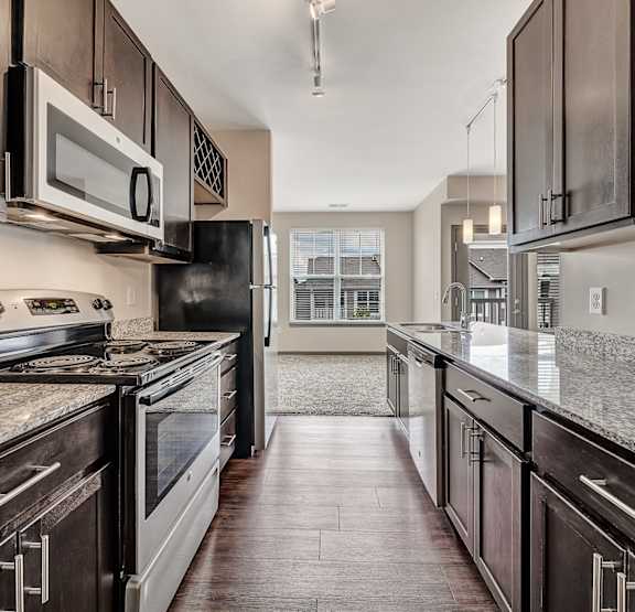  a kitchen with granite counter tops and wooden cabinets at Avellan Springs Apartments in Morrisville, NC 27560