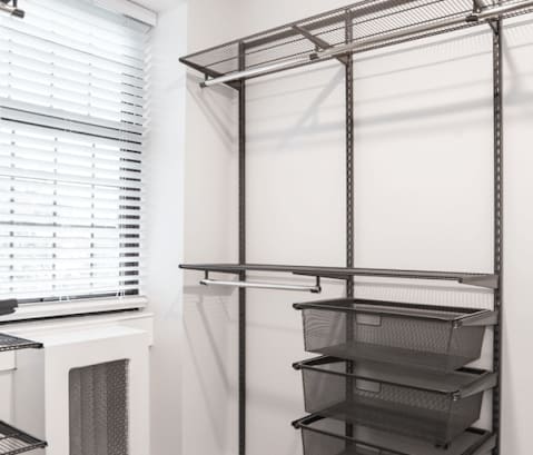 a walk in closet with black shelves and a window