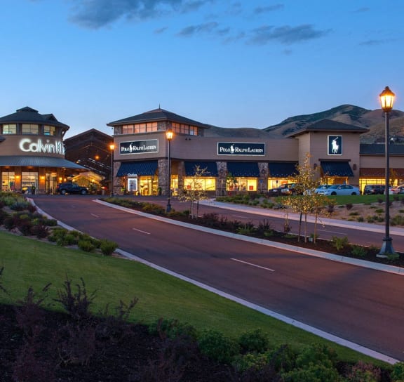 an exterior view of a shopping center at night with a road in front of it
