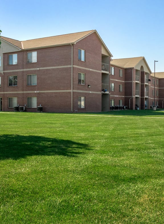 a large grassy area with a brick building in the background
