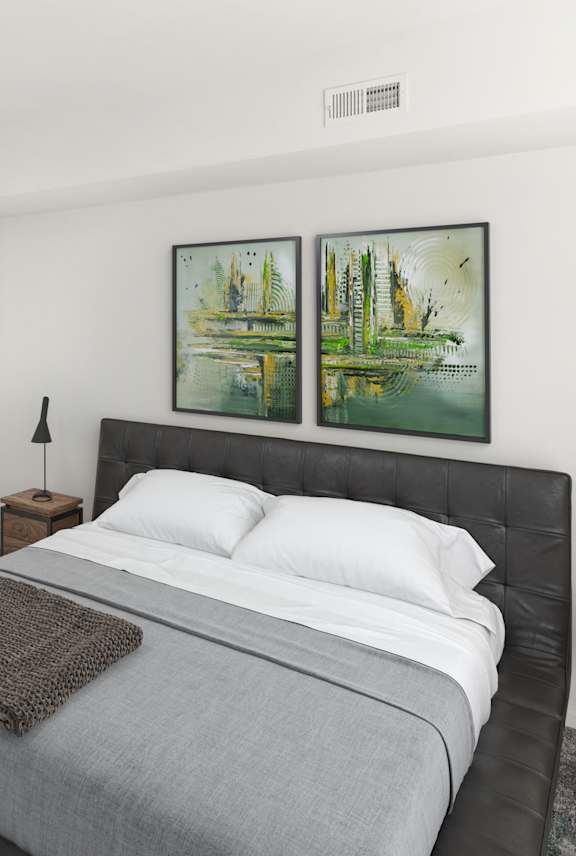 a white bedroom with a bed and two paintings on the wall