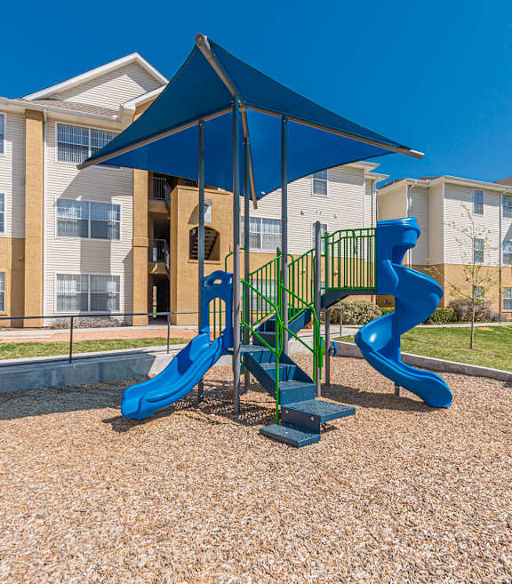 A playground with a blue slide and a canopy.