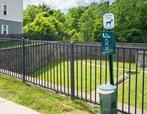 a black wrought iron fence with a green sign on it and a yard behind it