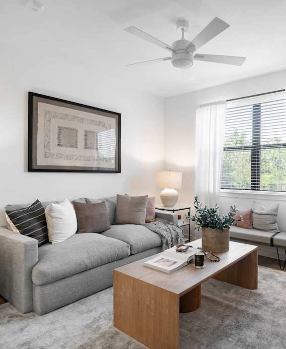 A living room with a grey couch, a coffee table, and a ceiling fan.