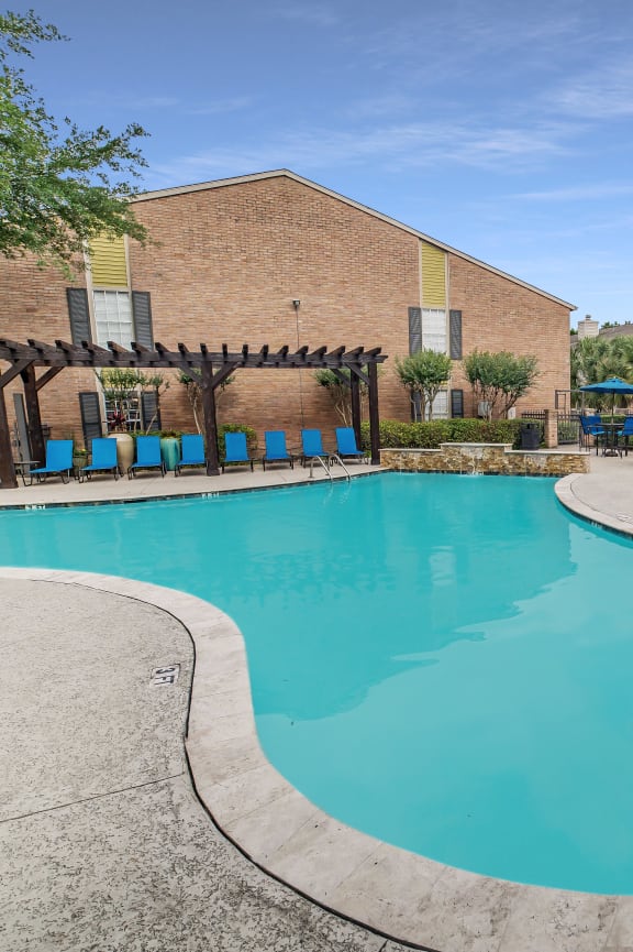 a swimming pool with orange chairs and a building in the background
