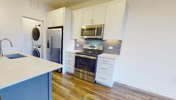 A modern kitchen with a blue island and white cabinets.