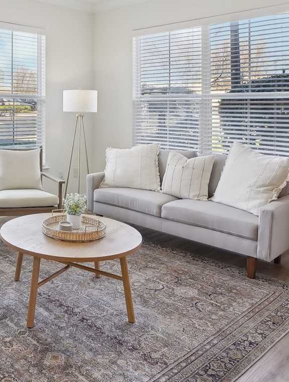 A living room with a white couch, a wooden coffee table, a flat screen TV, and a ceiling fan.