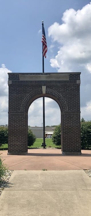 a stone arch with an american flag at the end of a walkway