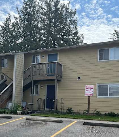 Apartment complex with a parking lot in front.