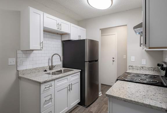 A kitchen with white cabinets and a black refrigerator.