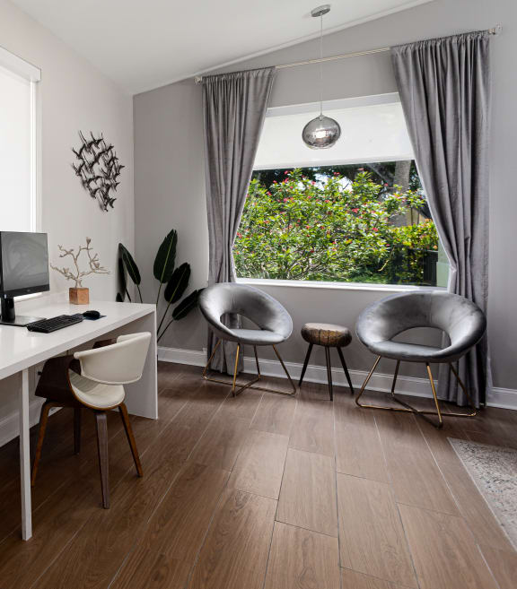 a home office with a large window and a white desk with two computer monitors