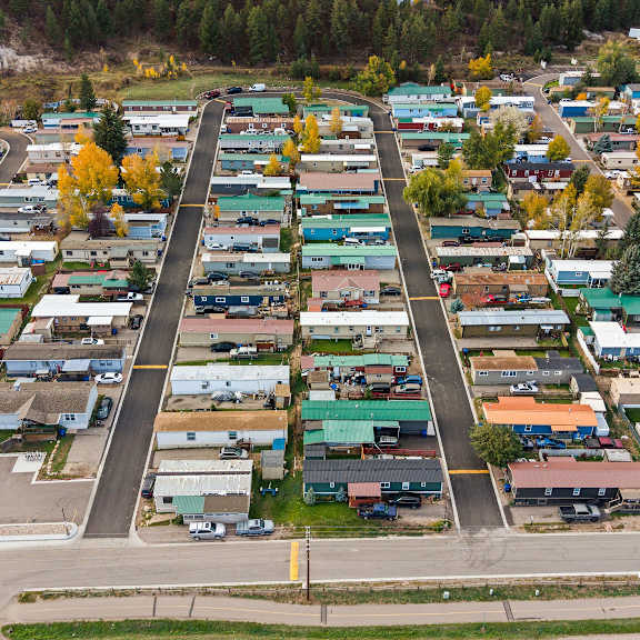 A parking lot with many cars and buildings in the background.