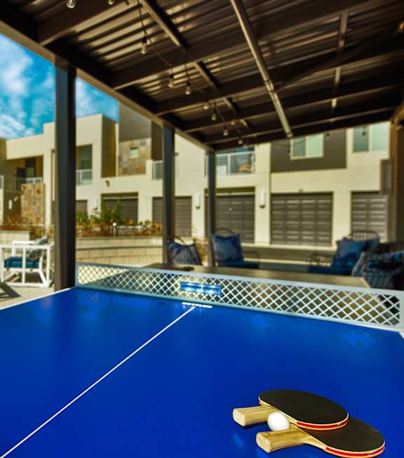 A blue ping pong table with two paddles on it. at Craft at Gilbert and Baseline Apartments, Arizona