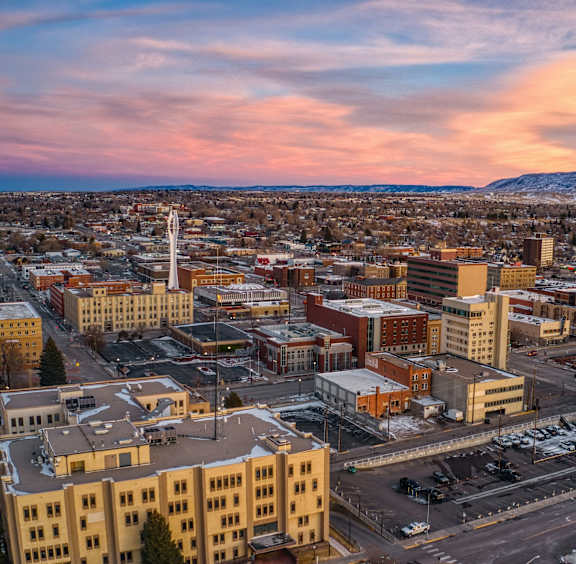 A cityscape with buildings and roads under a pink and blue sky.