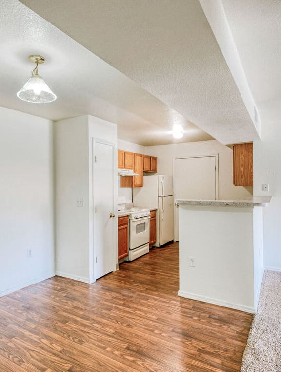 a renovated living room and kitchen with white walls and wood flooring