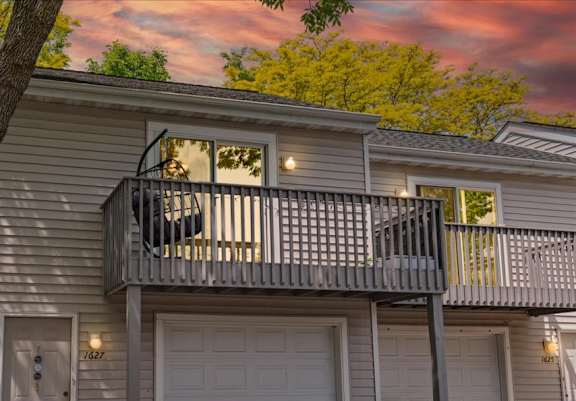 A two-story house with a balcony and garage doors.