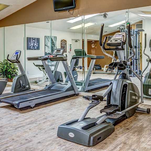 A gym with a variety of exercise equipment including treadmills, stationary bikes, and weights at Del Coronado Apartment , Mesa, Arizona
